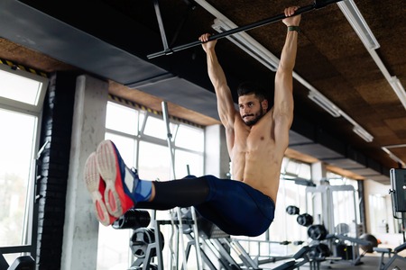 Young man performing hanging leg raises exercise