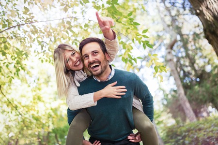 Handsome man giving his beautful girlfriend piggybackの写真素材