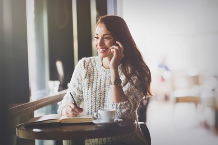 Beautiful woman talking on phone in restaurantの写真素材