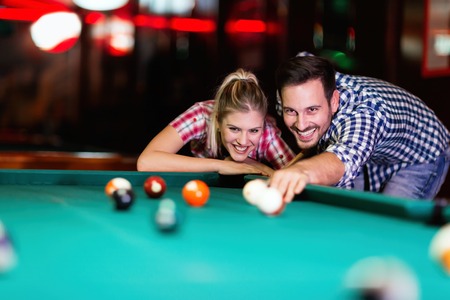 Young couple playing together pool in barの写真素材