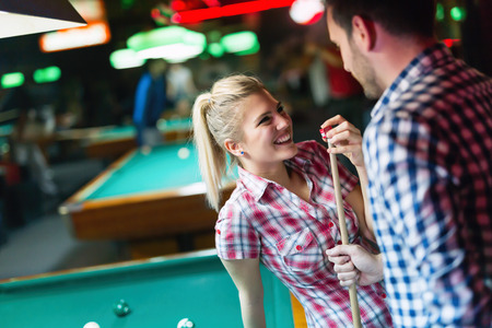 Happy couple drinking beer and playing snooker