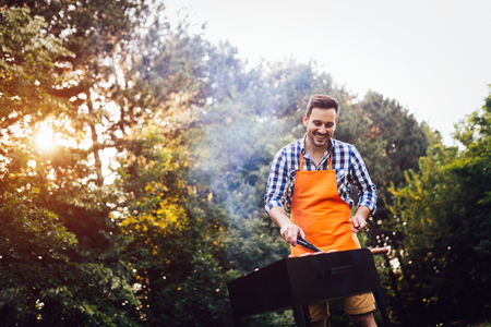 Handsome man preparing barbecue outdoors for friendsの写真素材