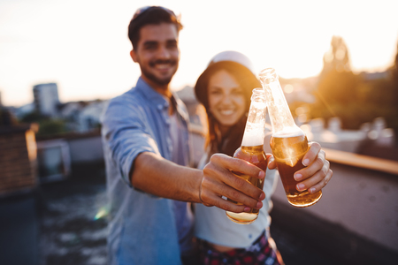 Young happy couple toasting with beer outdoorsの写真素材