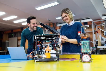 Young students of robotics preparing robot for testingの写真素材