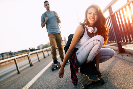 Young attractive couple riding skateboards and having funの写真素材