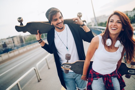 Picture of young attractive couple carrying skateboardsの写真素材