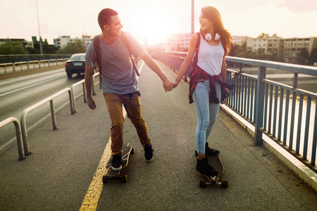 Young attractive couple riding skateboards and having funの写真素材