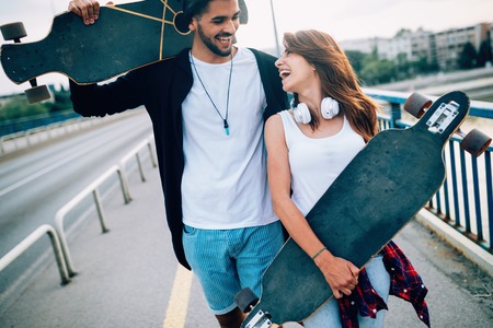 Picture of young attractive couple carrying skateboardsの写真素材