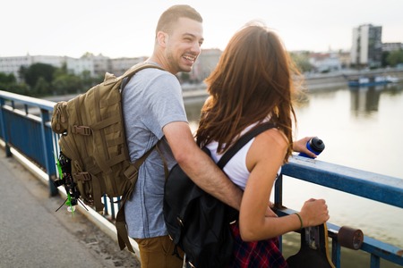 Picture of young attractive couple carrying skateboards