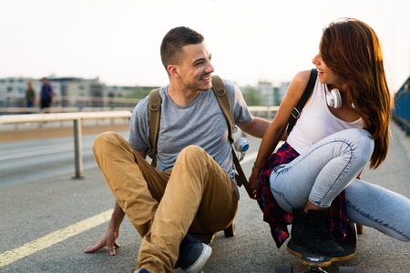 Young attractive couple riding skateboards and having funの写真素材