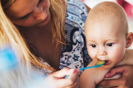 Portrait of mother feeding her baby with spoonの写真素材