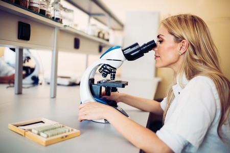 Young scientist looking through microscope in laboratoryの写真素材