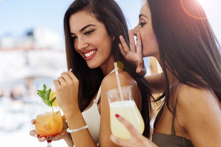 Glamorous girls drinking beverages on beachの写真素材