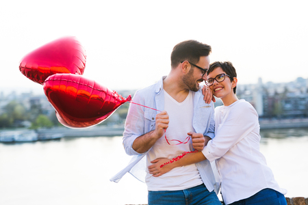 smiling couple in love with balloons on sunsetの写真素材