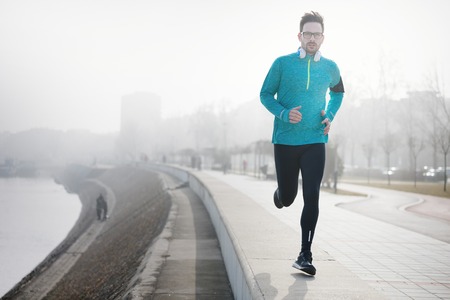 Determined sportsman fitness exercising by jogging outdoorの写真素材