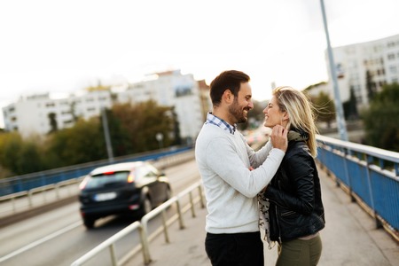 Happy young couple hugging and kissing on bridgeの写真素材