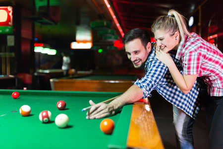 Young couple playing together pool in barの写真素材