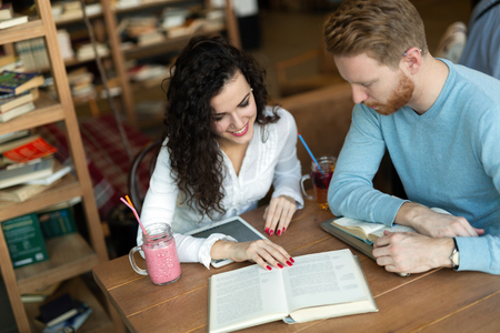 Young students spending time in coffee shop reading booksの写真素材