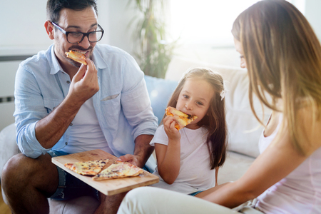 Happy family sharing pizza together at homeの写真素材