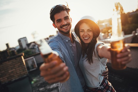 Young happy couple toasting with beer outdoorsの写真素材