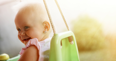 Happy cheerful baby smiling while on swingの写真素材