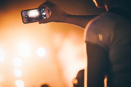 Girl recording video material on music festivalの写真素材