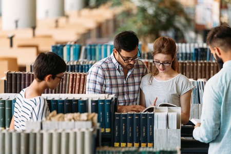 Young attractive students spending time in library