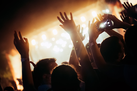 Cheering crowd with hands in air at music festivalの写真素材