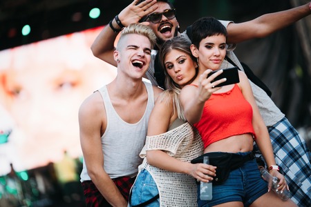Happy friends taking selfie at music festivalの写真素材