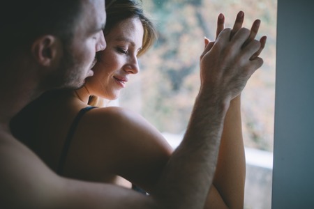 Attractive couple sharing intimate moments in bedroomの写真素材