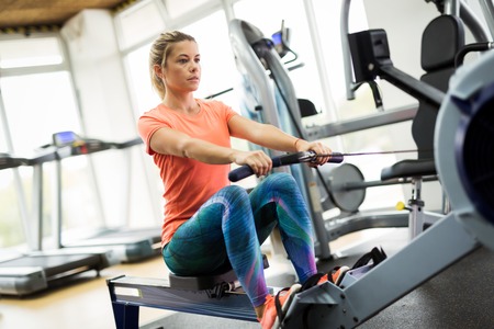 Young blonde woman working on rowing machine