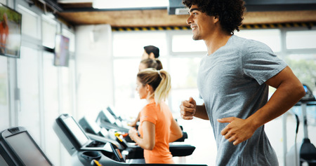 Young handsome man doing cardio training in gym