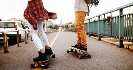 Young attractive couple riding skateboards and having fun