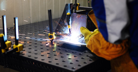 man welds at the factory working in metal industry