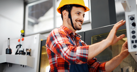 Industry Worker entering data in CNC machine at factory
