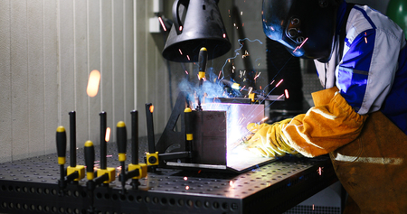 man welds at the factory working in metal industry