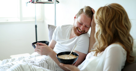 Young attractive couple having breakfast in bedの写真素材
