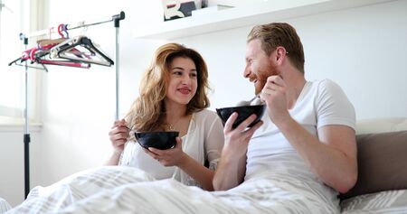Happy married couple being romantic in bed sharing cereal