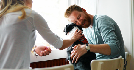 Beautiful couple relaxing at home and loving their dogの写真素材