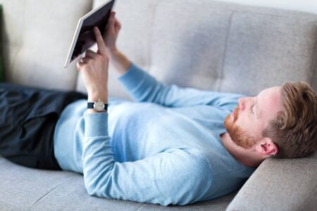 Young handsome man using digital tablet at home