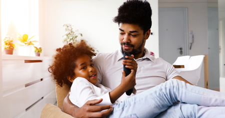 Father and daughter sitting on couch at homeの写真素材
