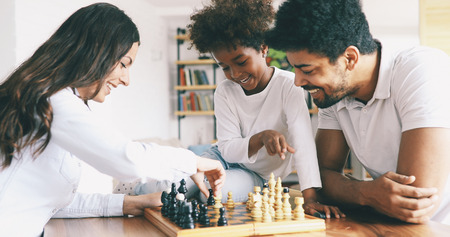 Happy family playing chess together at homeの写真素材