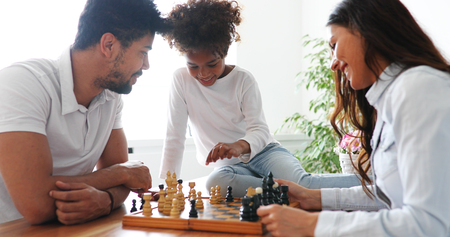 Happy family playing chess together at homeの写真素材