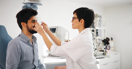 Optometrist examining patient in modern ophthalmology clinicの写真素材