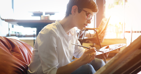 Creative pensive art school painter working on paintingの写真素材