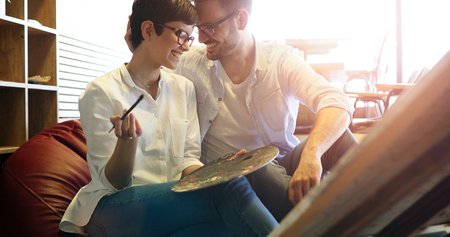 Beautiful young woman and a handsome man attending a painting workshop togetherの写真素材