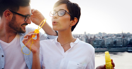 Happy couple dating and smiling while blowing bubbles