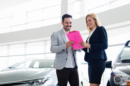 Professional salesperson selling cars at dealership to buyerの写真素材