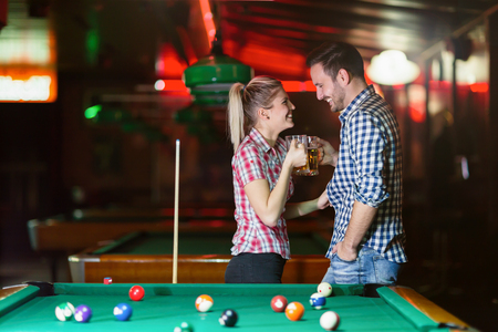 Happy couple drinking beer and playing snookerの写真素材