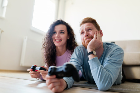 Happy couple playing video games at home